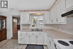 Kitchen featuring white cabinetry, a double basin stainless steel sink, and a four-burner electric range with an overhead vent -