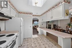 Kitchen featuring a skylight, white cabinetry, light-toned countertop, and patterned flooring -