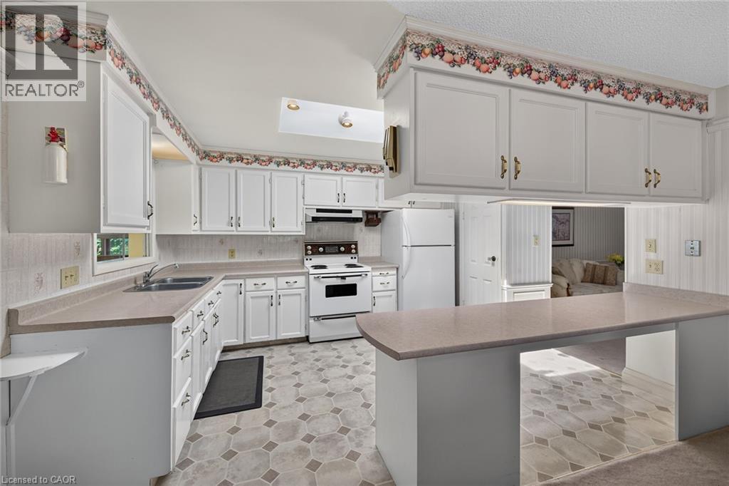 Kitchen featuring white cabinetry, light-toned countertops, integrated sink, and an electric range - 114 E Second Road E, Stoney Creek, ON