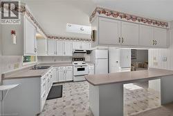 Kitchen featuring white cabinetry, light-toned countertops, integrated sink, and an electric range -