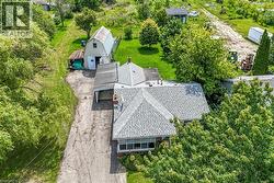 Property featuring a main residence with a gray shingle roof, an attached carport, and a separate barn structure -