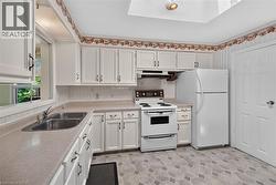 Kitchen featuring white cabinetry, a double basin stainless steel sink, and a light-toned countertop -