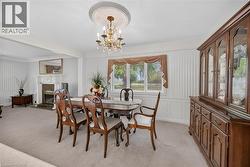 Formal dining area featuring a chandelier with a decorative ceiling medallion, a fireplace with a white mantel, and a large window with draped valances -