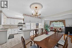 Kitchen and dining area featuring white cabinetry, a built-in breakfast bar, and a chandelier with decorative ceiling medallion -