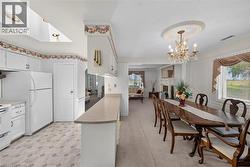 Kitchen and dining area featuring a skylight, white cabinetry, light-toned countertops, and a decorative chandelier with an ornate ceiling medallion -