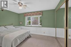 Room featuring a bay window with a valance, white wainscoting, and carpet flooring -