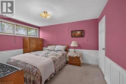 Room featuring upper walls in a deep pink hue, white wainscoting, and carpeted flooring -