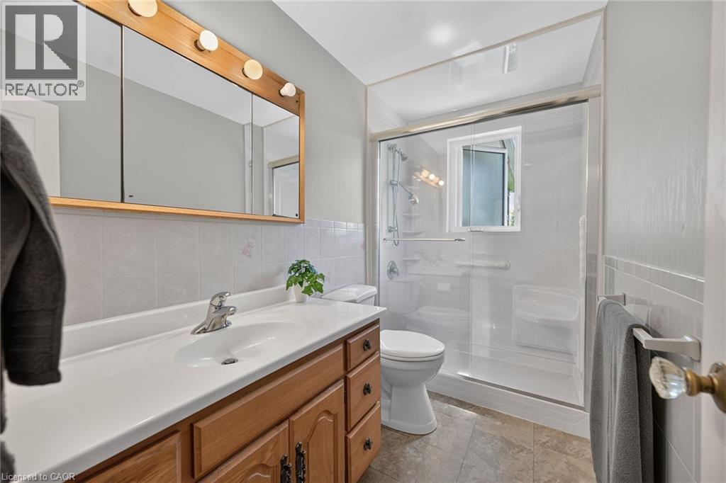 Bathroom featuring a wood-finish vanity with an integrated sink and chrome faucet - 114 E Second Road E, Stoney Creek, ON