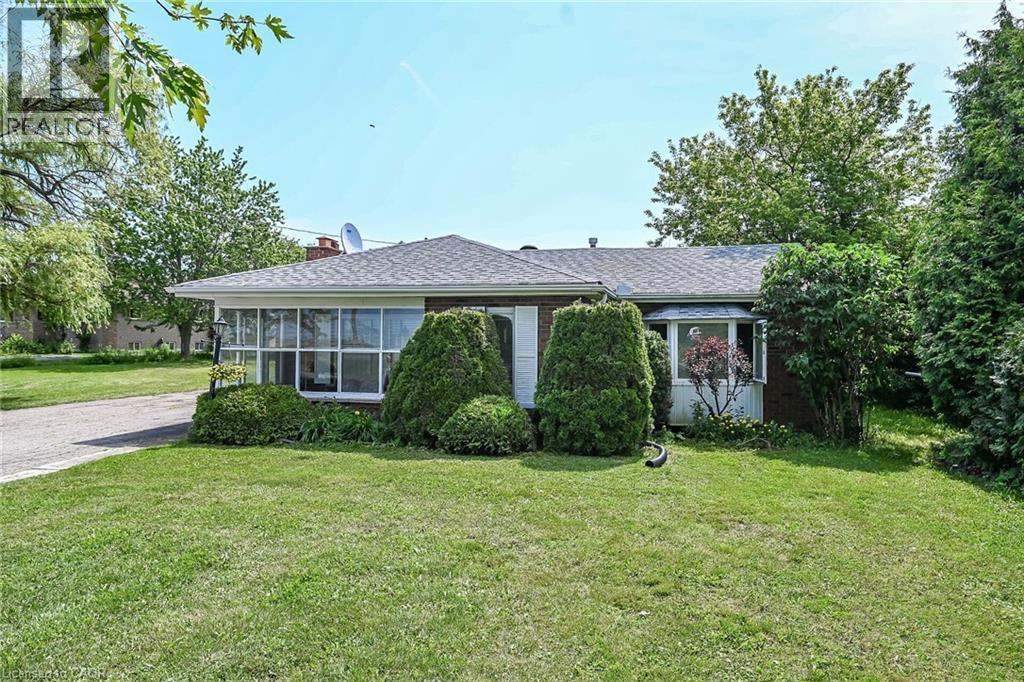 Brick exterior with a gabled roofline, a bay window, and a sunroom with multiple pane windows - 114 E Second Road E, Stoney Creek, ON