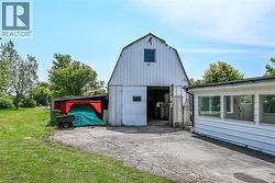 Large white barn structure with a gambrel roof and an open ground-level entrance -