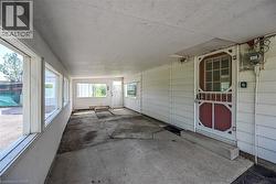 Enclosed porch featuring multiple windows, a ceiling fan, concrete flooring, and a red screen door -