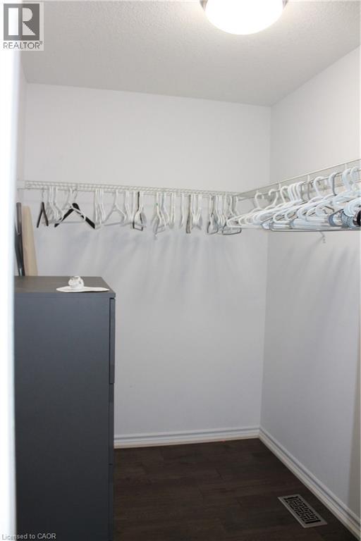 Walk-in closet featuring wood-finish flooring, white baseboards, and a built-in wire shelving system - 27 Stillwater Street, Kitchener, ON