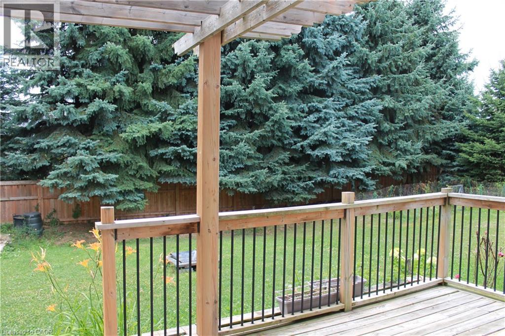 Expansive wood deck featuring a pergola, wood railing with black balusters, and a green lawn - 27 Stillwater Street, Kitchener, ON