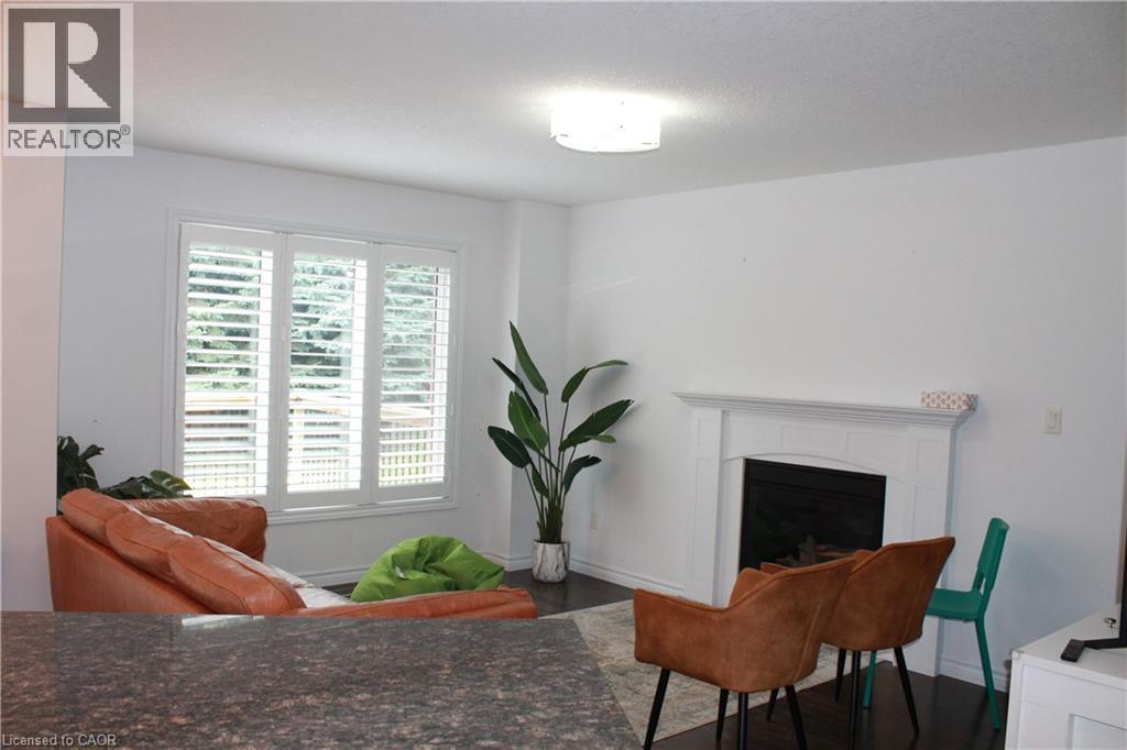 Living space featuring dark wood-finish flooring, white walls, and a recessed fireplace with a white mantel - 27 Stillwater Street, Kitchener, ON