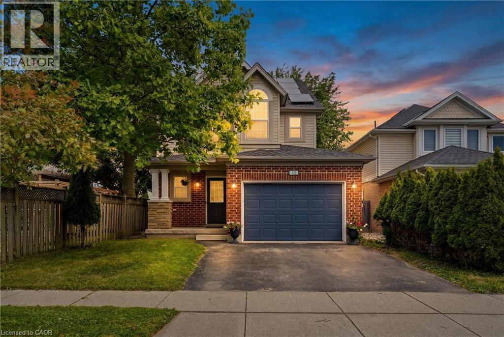 Brick and siding exterior featuring an attached garage with a paneled door, a covered front entry, and a paved driveway - 128 Houghton Street, Cambridge, ON