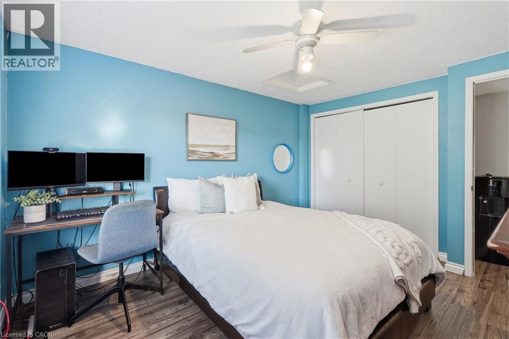 Bedroom featuring wood-finish flooring, a ceiling fan, and white bi-fold closet doors - 128 Houghton Street, Cambridge, ON
