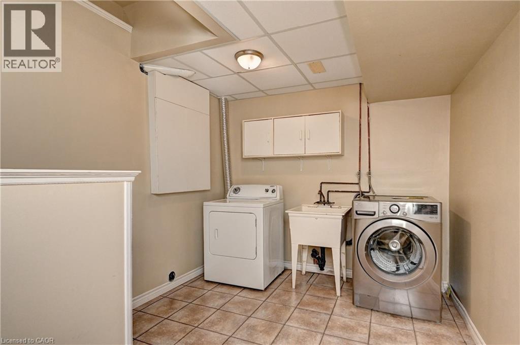 Dedicated laundry area featuring ceramic tile flooring, a utility sink, and wall-mounted cabinetry - 760 Paris Boulevard, Waterloo, ON