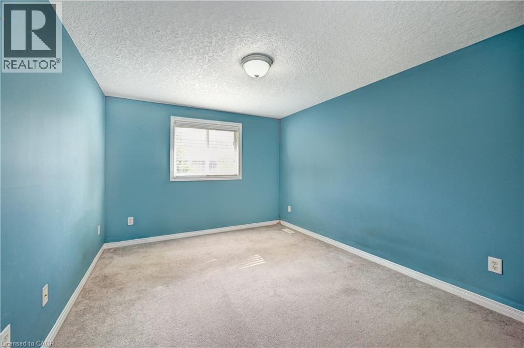 Carpeted interior room with blue painted walls, a white trim window, and a flush mount ceiling light fixture - 760 Paris Boulevard, Waterloo, ON