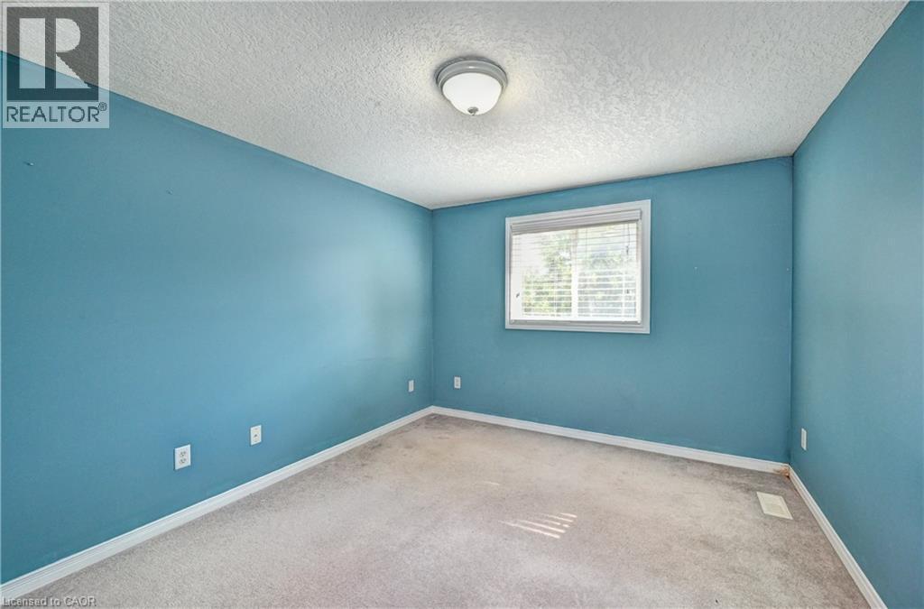 Carpeted room with a single window featuring white horizontal blinds, white baseboards, and a semi-flush mount ceiling light fixture - 760 Paris Boulevard, Waterloo, ON