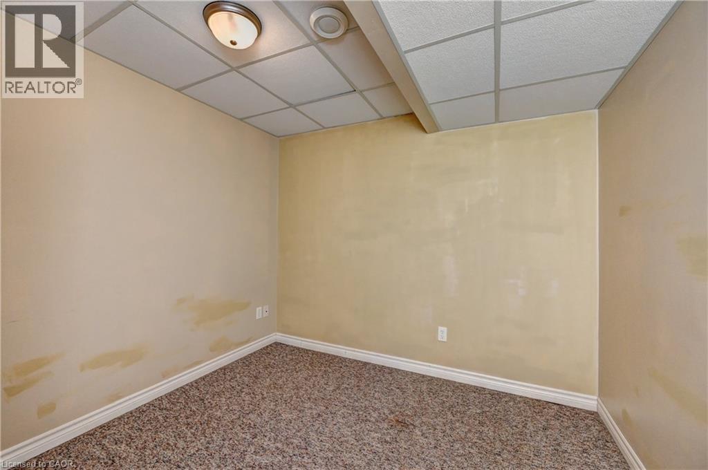 Interior space featuring drop panel ceiling, flush-mount lighting fixture, and speckled carpet flooring - 760 Paris Boulevard, Waterloo, ON
