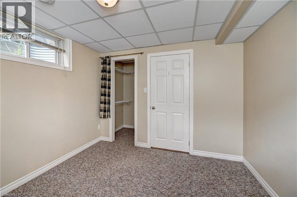 Carpeted room featuring a drop ceiling, white trim, and neutral wall tones - 760 Paris Boulevard, Waterloo, ON