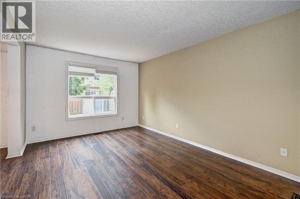 Room featuring wood-finish flooring, a large window, a neutral-toned wall, and white trim - 760 Paris Boulevard, Waterloo, ON