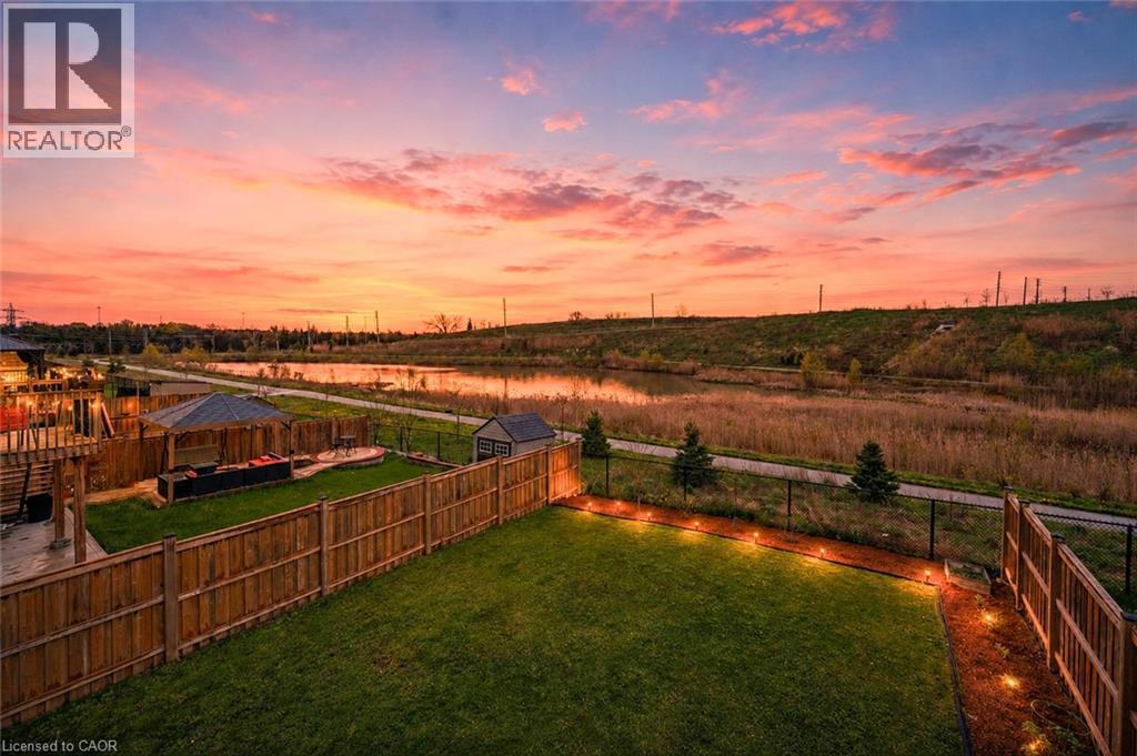 Expansive backyard featuring a manicured lawn, wood fencing, and perimeter lighting - 87 Ridge Road, Cambridge, ON