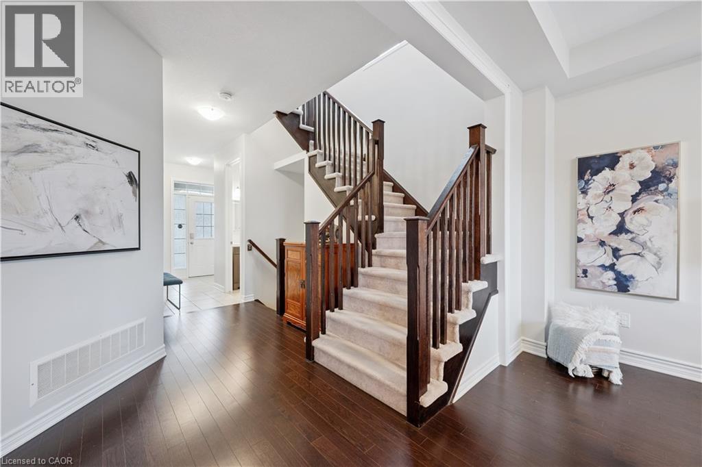 Grand staircase featuring dark wood newel posts and balusters, carpeted treads, and a rich wood-finish flooring - 87 Ridge Road, Cambridge, ON