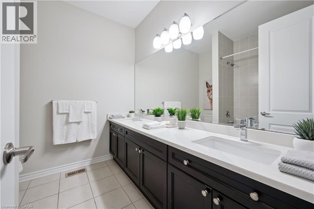 Bathroom featuring a dual-sink vanity with white countertops, dark wood cabinetry, and chrome hardware - 87 Ridge Road, Cambridge, ON