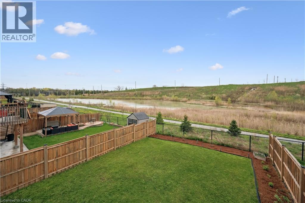 Expansive green lawn framed by a wooden fence, featuring a paved patio area, a gazebo, and a storage shed - 87 Ridge Road, Cambridge, ON