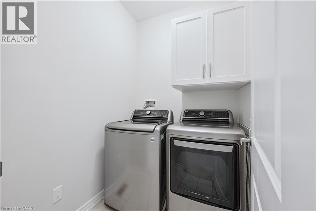 Dedicated laundry area featuring white shaker-style cabinetry, a built-in shelf, and baseboard trim - 87 Ridge Road, Cambridge, ON