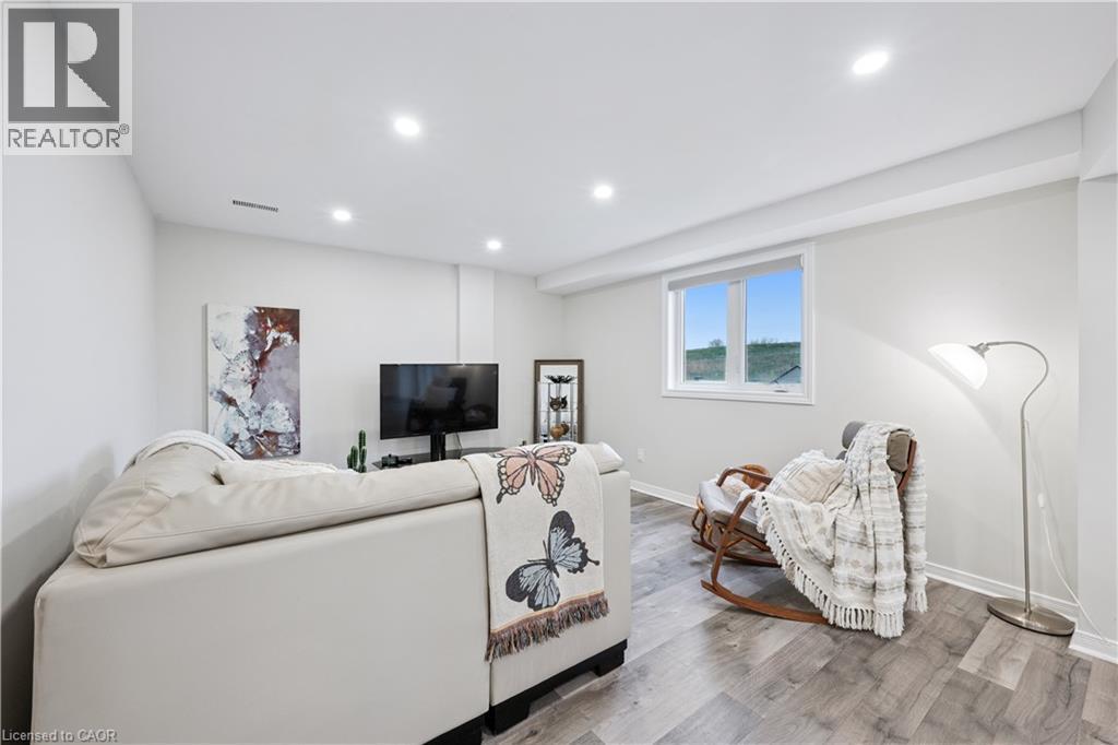 Spacious living area featuring light gray walls, recessed lighting, and wood-finish flooring - 87 Ridge Road, Cambridge, ON