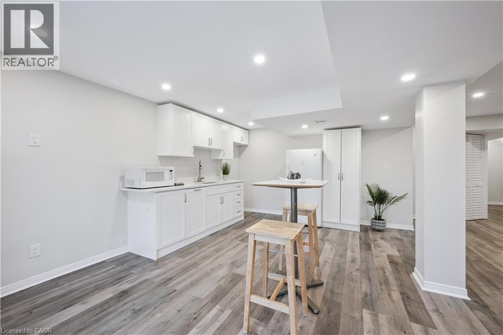 Kitchenette featuring white cabinetry, a sink, and a white refrigerator - 87 Ridge Road, Cambridge, ON