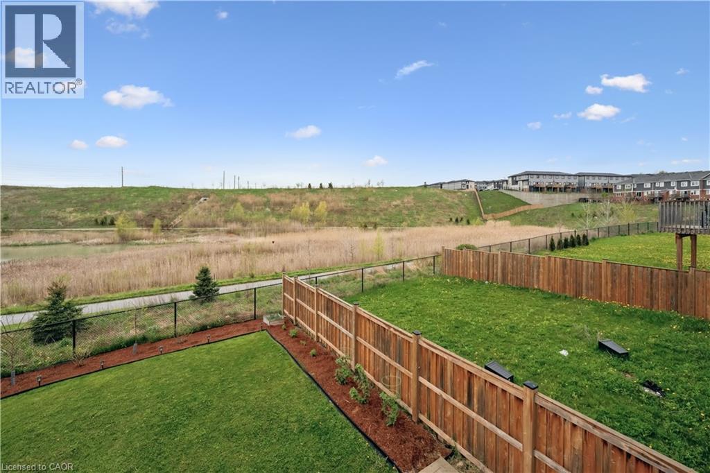 Expansive backyard featuring a lush lawn, privacy fencing, and a mulched garden bed - 87 Ridge Road, Cambridge, ON