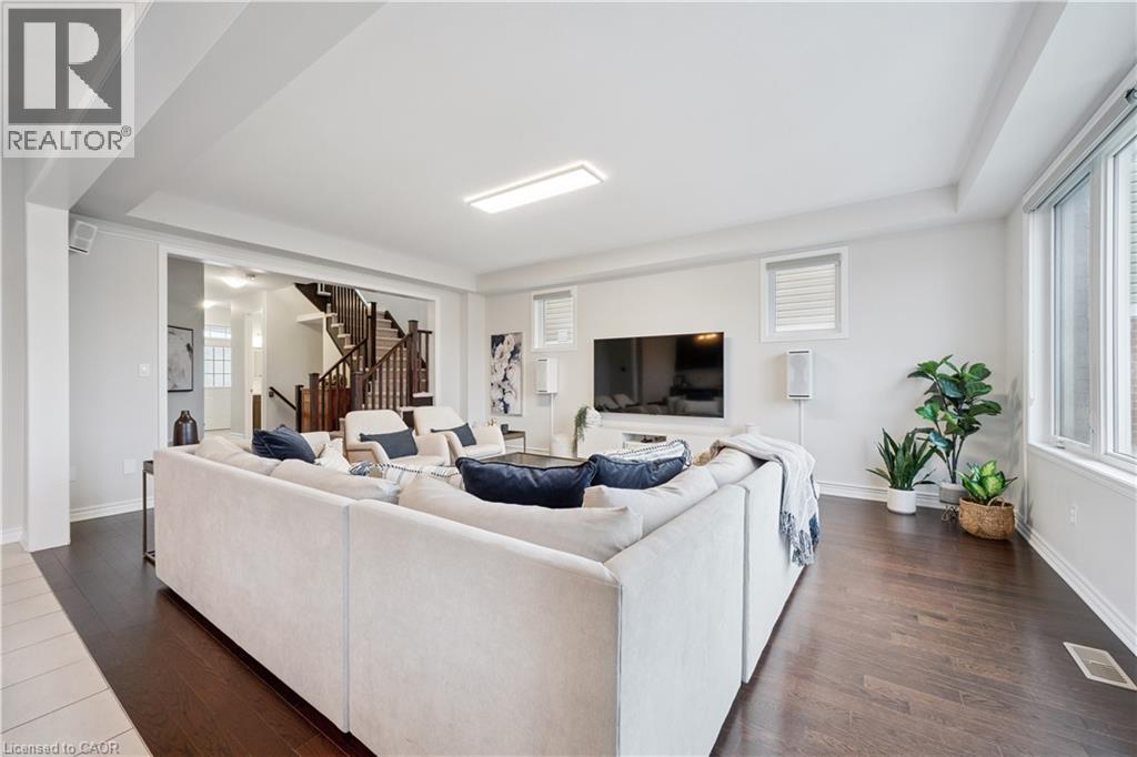 Spacious living area featuring dark wood-finish flooring, white walls, and bright overhead lighting - 87 Ridge Road, Cambridge, ON