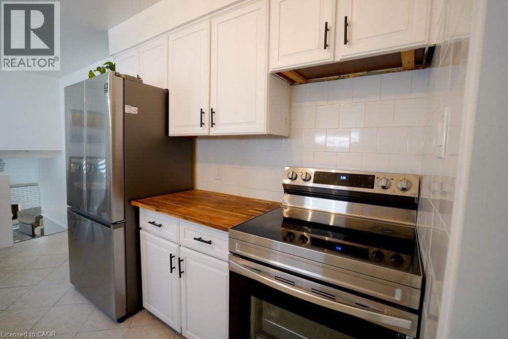 Kitchen featuring new stainless steel appliances, white shaker-style cabinetry with matte black hardware, butcher block countertops, and a subway tile backsplash - 147 Muriel Crescent, London, ON