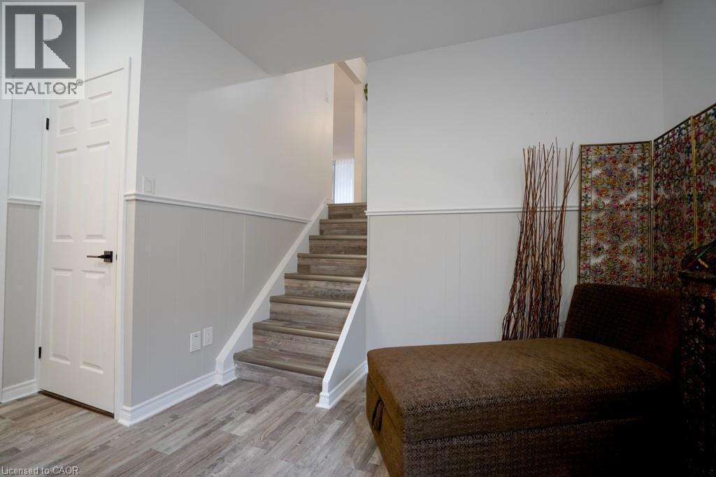 Staircase featuring wood-finish treads and risers, white stringers, and a prominent wainscoting detail - 147 Muriel Crescent, London, ON