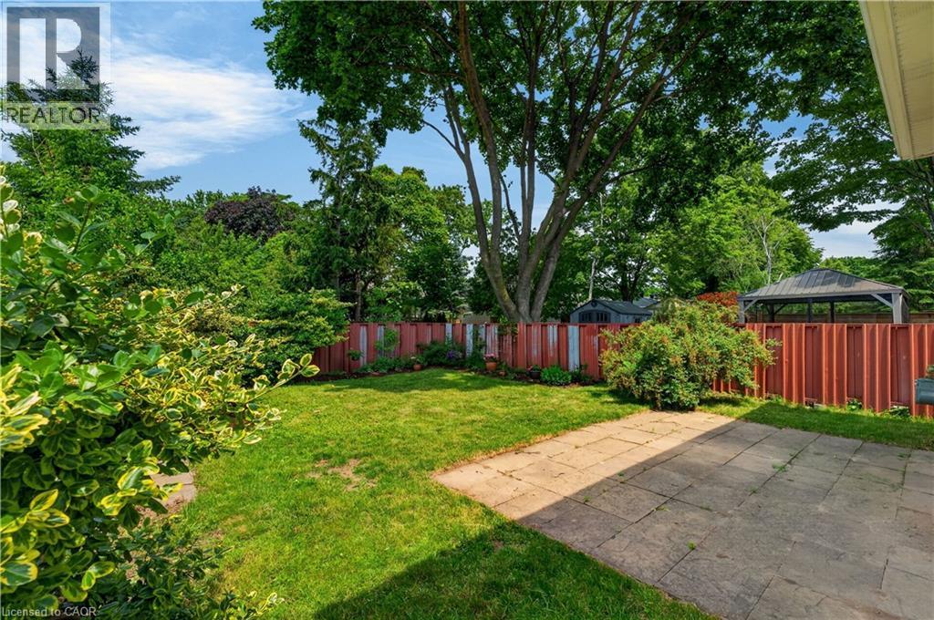 Spacious fully-fenced backyard featuring patio and mature trees - 5051 Brady Avenue, Burlington, ON