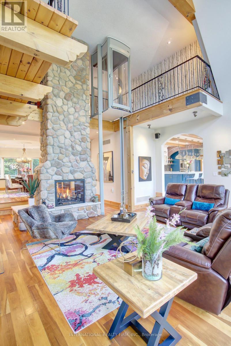 Commanding double-sided stone gas fireplace. - 6 Pinehurst Lane, Springwater, ON - Indoor With Fireplace