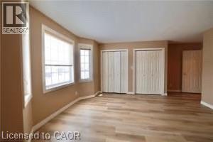Spacious room featuring light wood-finish flooring, neutral wall tones, and white baseboards - 17 Hawkswood Drive, Kitchener, ON