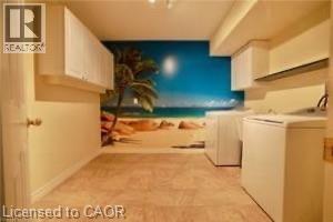 Utility room featuring a tiled floor, built-in cabinetry, and a beach-themed wall mural - 17 Hawkswood Drive, Kitchener, ON