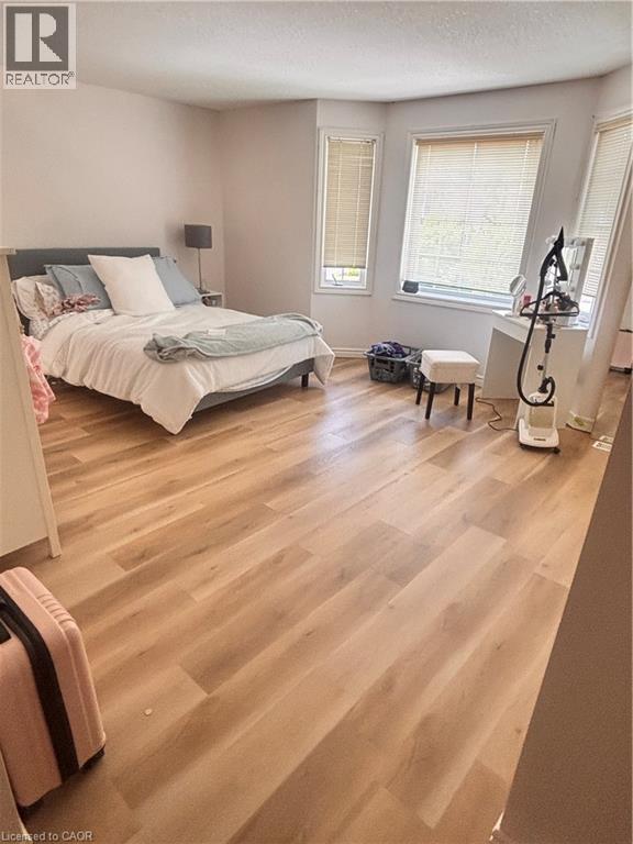 Spacious room featuring light wood-finish flooring, light-toned walls, and multiple windows with blinds - 17 Hawkswood Drive, Kitchener, ON