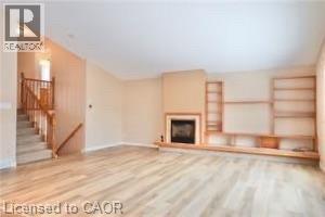 Spacious living area featuring light wood-finish flooring, a central fireplace with a mantel, and extensive built-in shelving - 17 Hawkswood Drive, Kitchener, ON