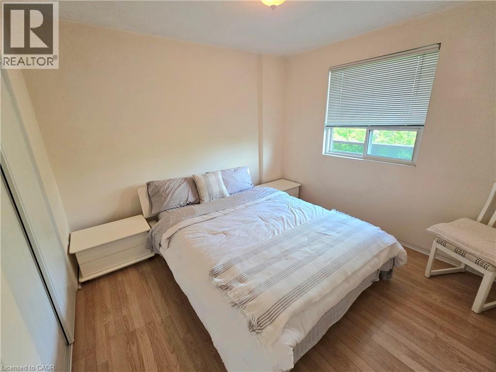 Bedroom featuring wood-finish flooring and a single window with horizontal blinds - 2373 E King Street E Unit# 37, Hamilton, ON
