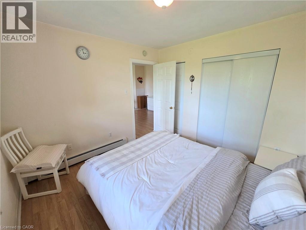 Bedroom featuring wood-finish flooring, light-toned walls, and a ceiling light fixture - 2373 E King Street E Unit# 37, Hamilton, ON