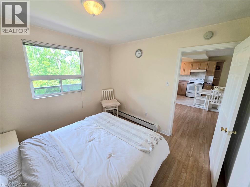 Bedroom featuring a single window, baseboard heating, wood-finish flooring, and a flush-mount ceiling light - 2373 E King Street E Unit# 37, Hamilton, ON