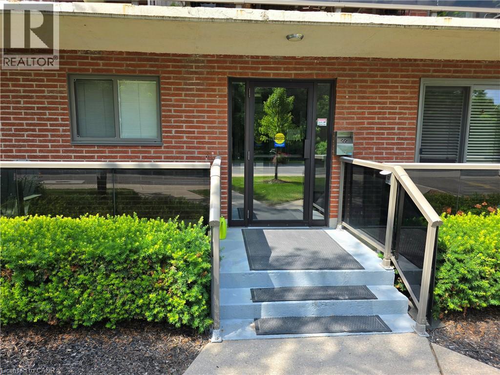 Brick exterior with a glass-paneled entry door, concrete steps, and a glass-paneled railing system - 2373 E King Street E Unit# 37, Hamilton, ON