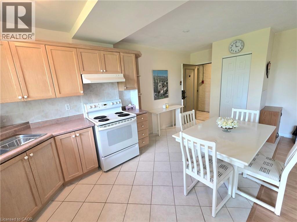 Kitchen and dining area featuring light wood-finish cabinetry, a white electric range, and a tile backsplash - 2373 E King Street E Unit# 37, Hamilton, ON
