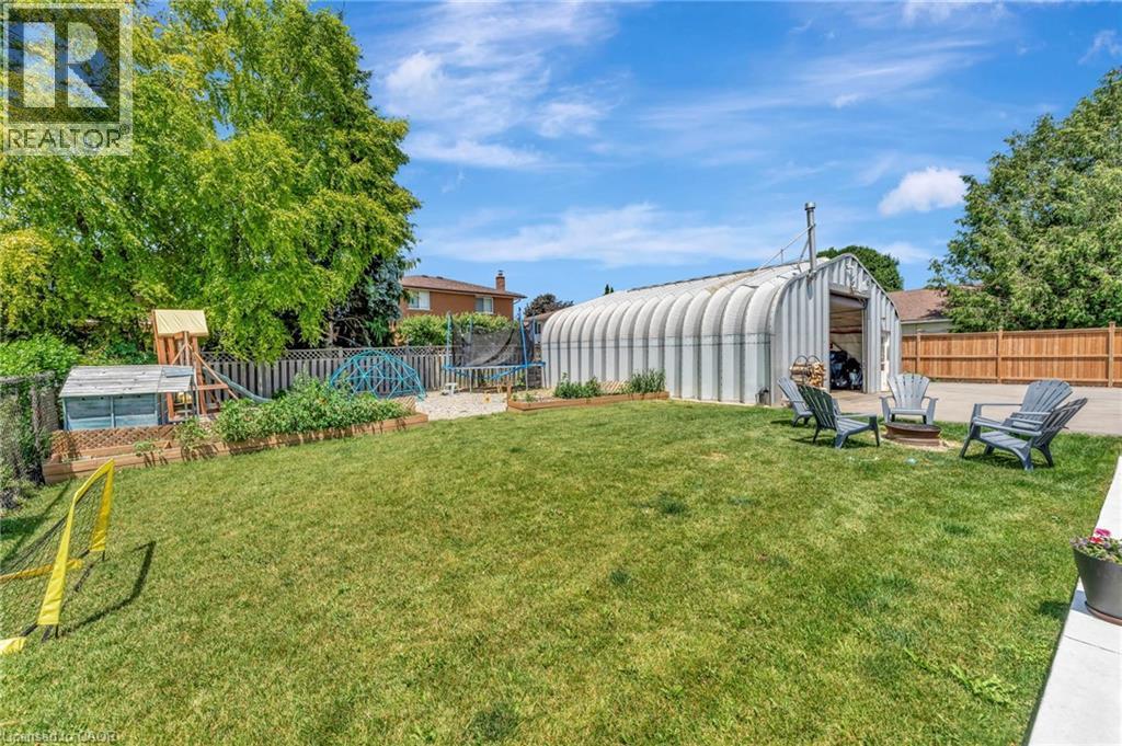 Expansive backyard featuring a large metal quonset hut, a dedicated fire pit area, a level lawn, and mature perimeter trees - 192 Myers Road, Cambridge, ON