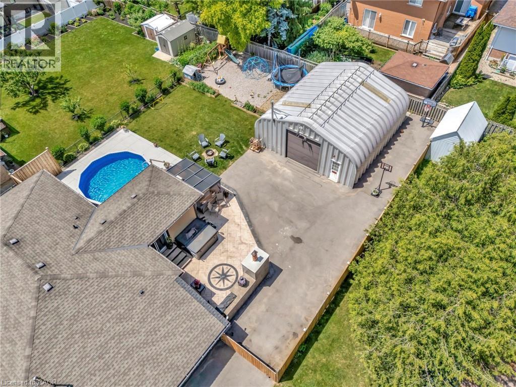Expansive rear yard featuring an above-ground pool, a concrete patio with an integrated hot tub, and a decorative compass rose medallion - 192 Myers Road, Cambridge, ON